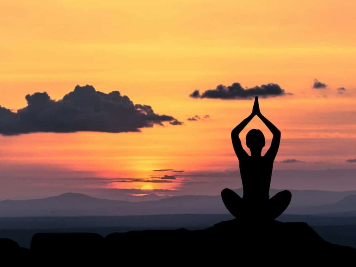 Uno splendido scatto di una ragazza che medita davanti allalba