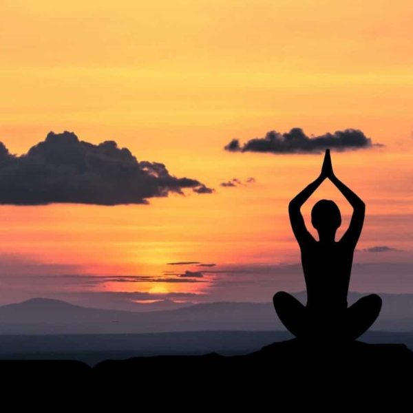 Uno splendido scatto di una ragazza che medita davanti allalba